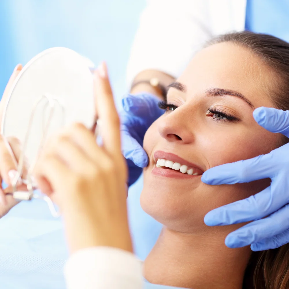 Patient checking smile in mirror after successful root canal treatment at Hanlon Creek Dental in Guelph, ON
