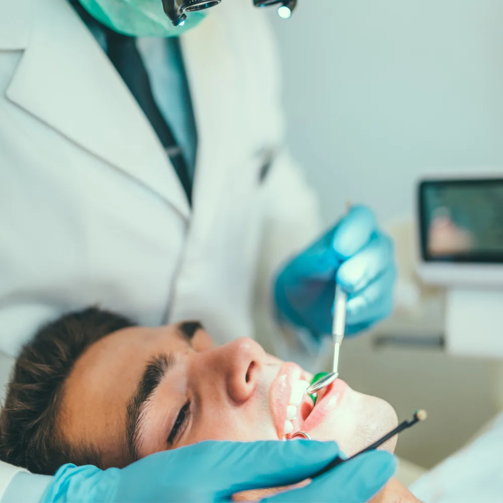 Dentist performing dental treatment on a male patient using professional dental instruments at Hanlon Creek Dental, Guelph ON.