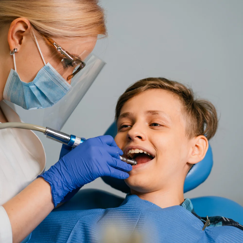 Child receiving gentle dental cleaning from dentist, smiling comfortably during pediatric exam at Hanlon Creek Dental in Guelph, ON