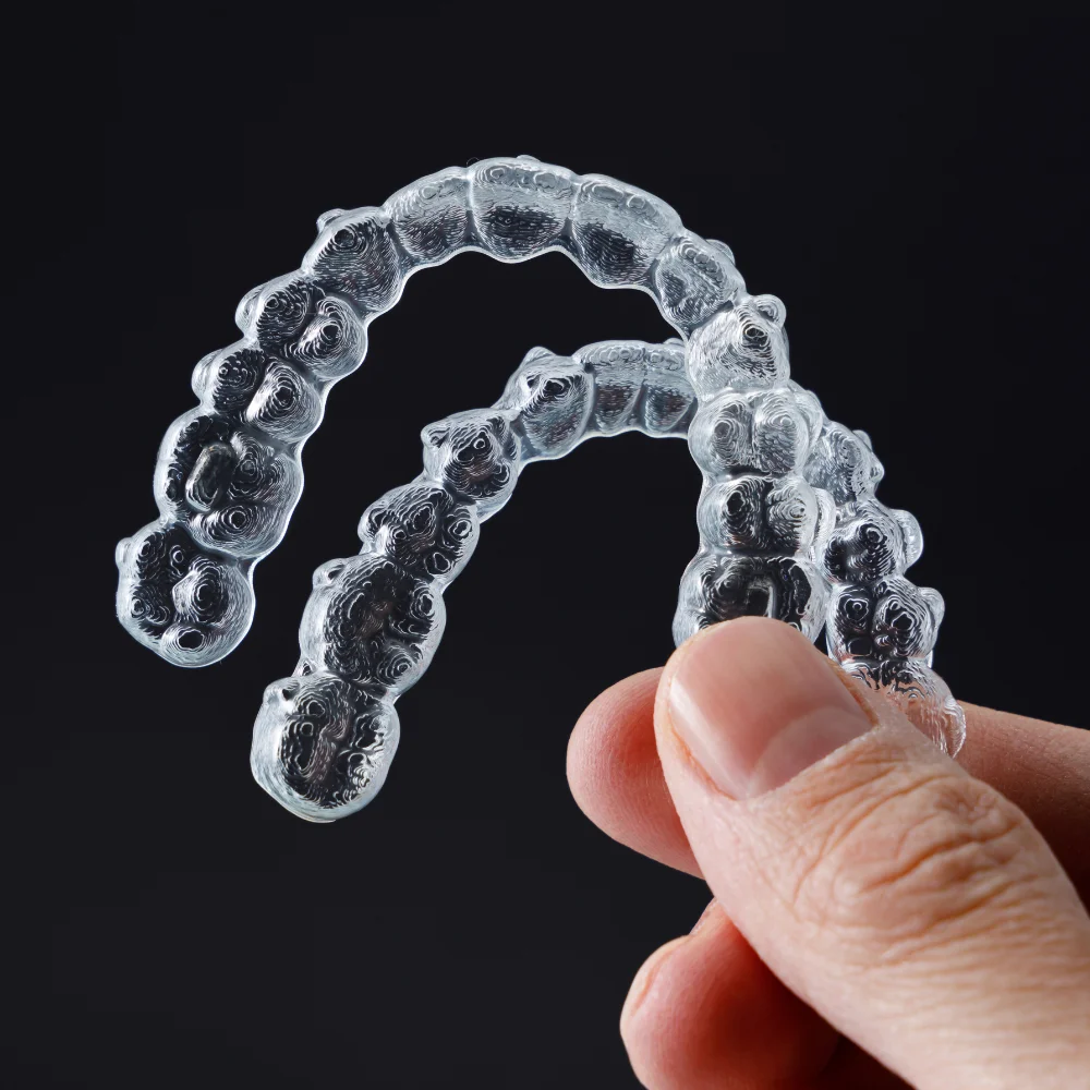 Clear dental aligners held by a hand at Hanlon Creek Dental, Guelph ON, used for orthodontic teeth straightening.