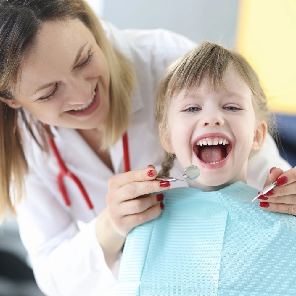 Female dentist examining a smiling young child during a pediatric dental check-up in a Hanloncreek Dental dental Guelph, ON