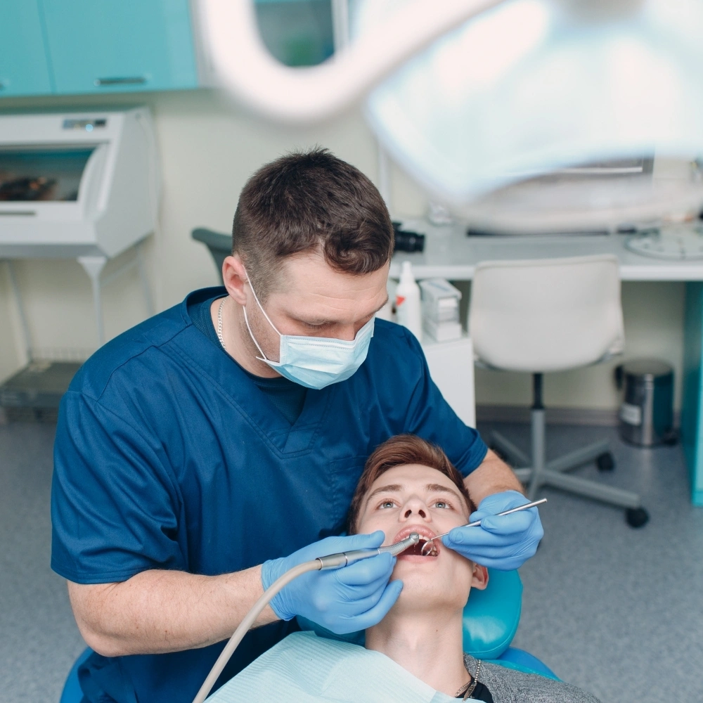 Dentist performing routine dental check-up on teenage patient at Hanlon Creek Dental in Guelph, ON
