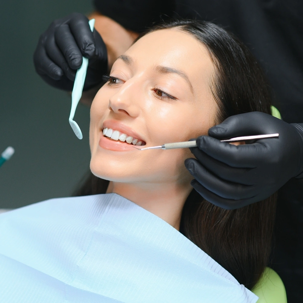 Adult patient receiving cosmetic dental treatment from dentist using precision tools