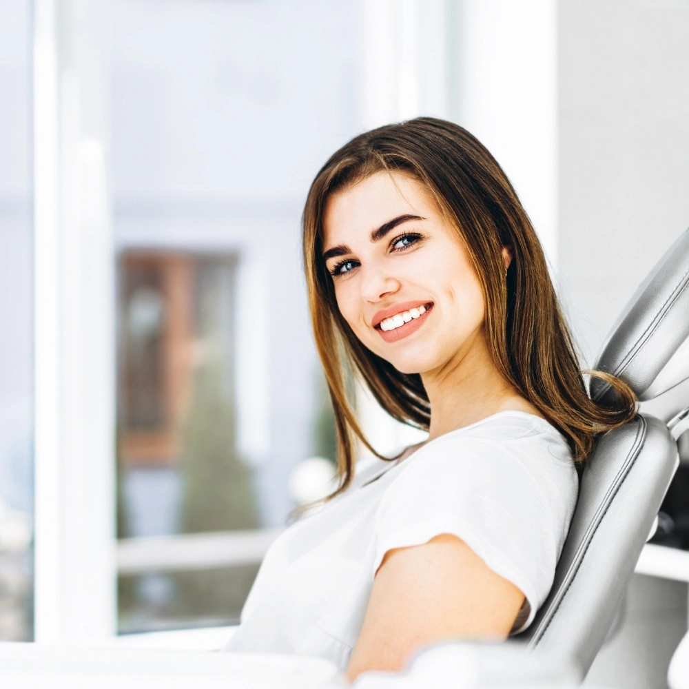 Smiling female patient sitting comfortably in the dental chair after treatment at Hanlon Creek Dental in Guelph, ON.