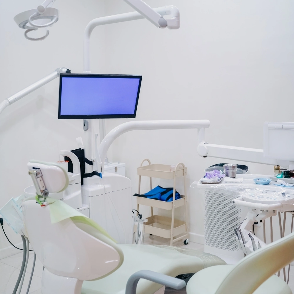 Modern dental treatment room at Hanlon Creek Dental in Guelph, ON featuring a dental chair, overhead light, sterilized instruments, and a mounted display screen prepared for patient care.