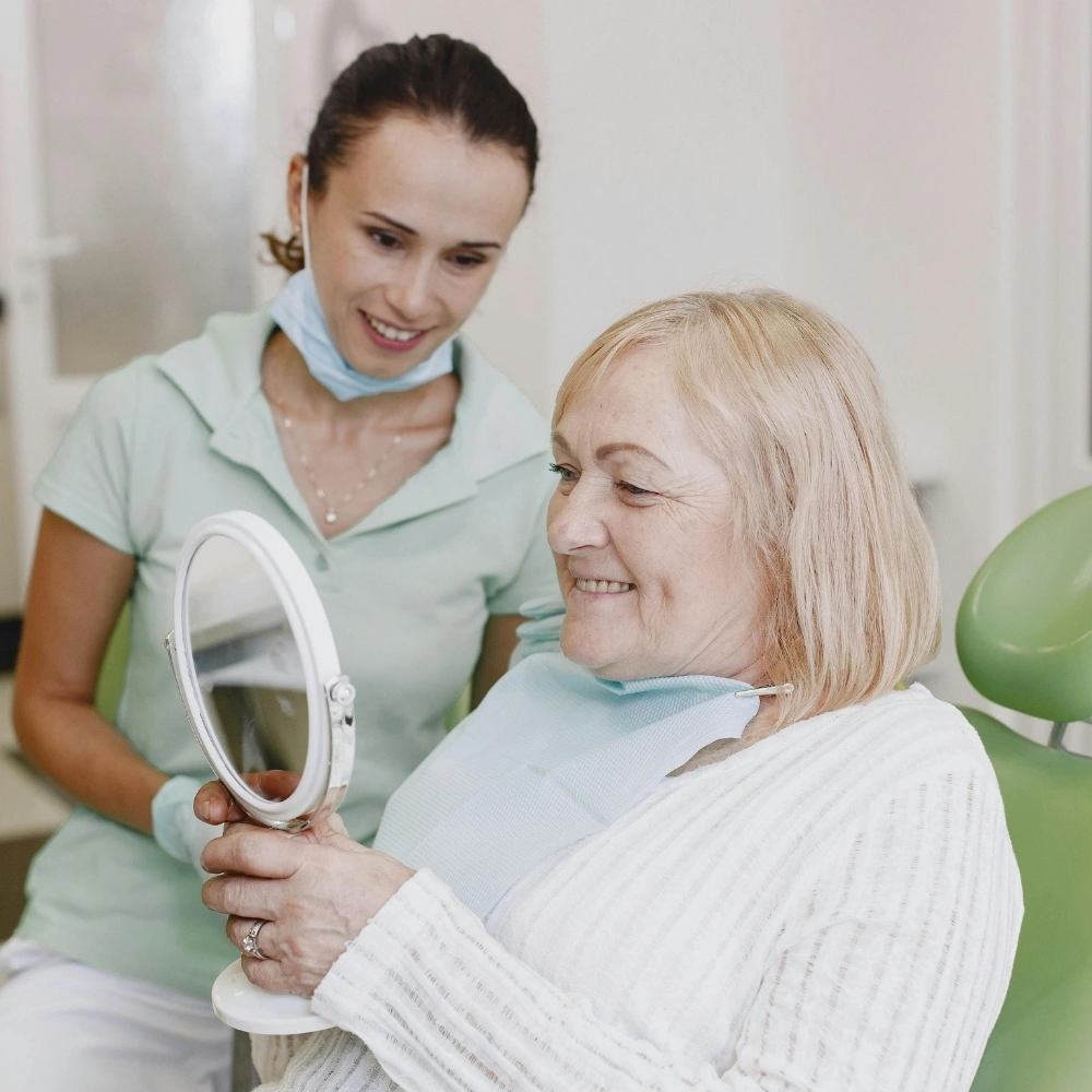 Senior patient checking new dentures with dentist support at Hanlon Creek Dental in Guelph