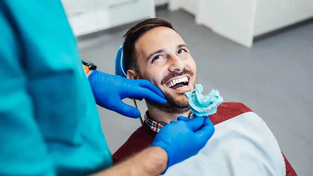 Adult patient smiling while dentist takes dental bridge impression at Hanlon Creek Dental in Guelph, ON