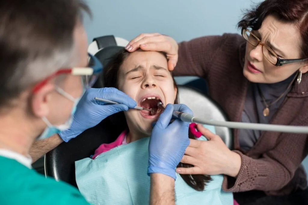 Child experiencing a dental emergency receiving urgent care from a dentist, supported by a parent, at Hanlon Creek Dental in Guelph, ON